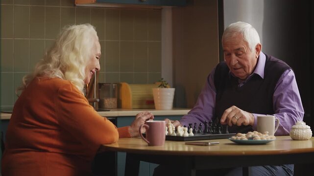 Smiling elderly couple playing chess at home, enjoying favorite hobby