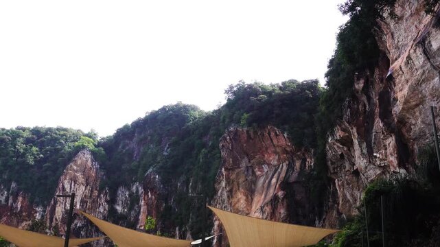 Scenic view of a limestone hill located at the entrance to Tasik Cermin tunnel in Ipoh, Perak, Malaysia. Natural rock formations surrounded by tropical landscape creating a peaceful travel and geologi