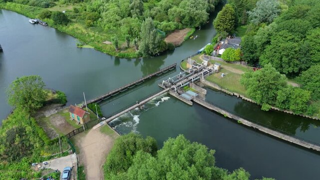 Aerial view of Feildes Weir Lock on the River Lee with calm water and lush green trees along the banks in Hoddesdon, England, United Kingdom.
