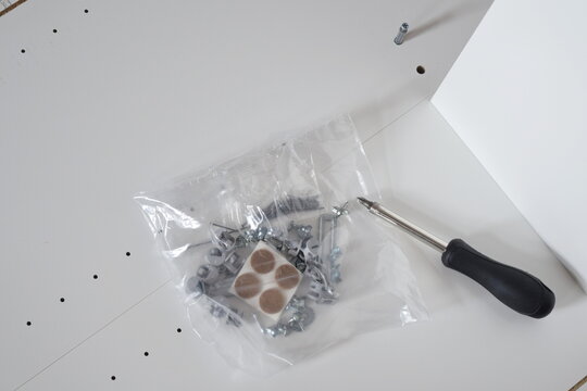 Unassembled white wooden furniture parts screws and hand tool closeup diy home renovation concept	 