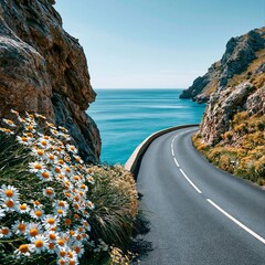 Fototapeta premium Coastal road curves along the sea with flowers blooming in the foreground on a clear day