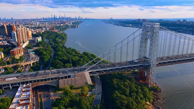 Lush greenery covering the waterfront of the Hudson River near the George Washington Bridge. Washington Heights in Upper Manhattan at sunset from drone.