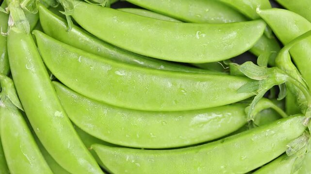 Pile of fresh raw sugar snap peas rotating slowly. Top view shot