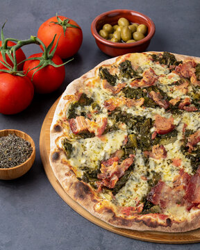 Endive, bacon and mozzarella pizza with tomatoes, eggs and flour over stone background
