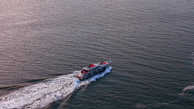 Following a motor boat moving by the waterscape. A group of people are having rest at the vessel.