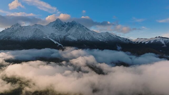 High Tatras, Slovakia - 4K flying by the High Tatras mountains above clouds on a foggy autumn day with blue sky and clouds