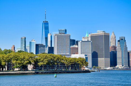 Blue two-masted schooner sailing vessel docked at pier with warehouse and Brooklyn skyline in background, New York Harbor, NYC, USA