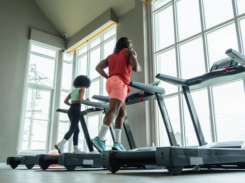 Diverse people running on treadmills modern gym with natural light representing healthy lifestyle cardiovascular training fitness community wellness amenities real estate healthcare marketing