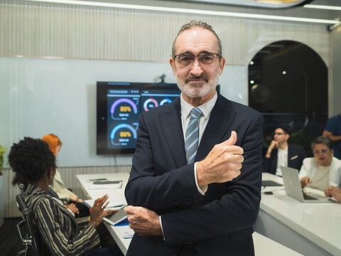 Confident Senior Executive Giving Thumbs Up. professional senior businessman suit gesture in modern digital office, symbolizing corporate success, approval, experienced leadership