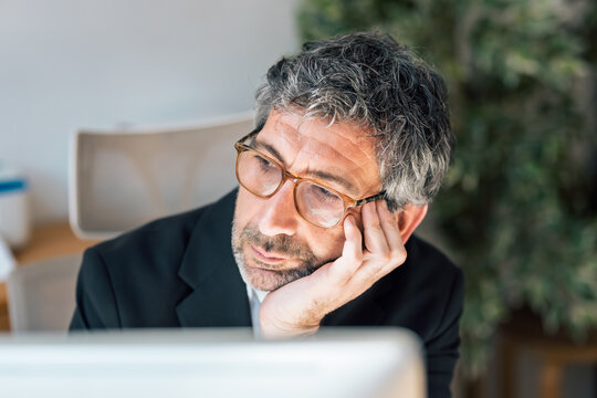 Distracted businessman looking outside while working on a computer in the office