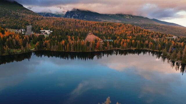 Strbske Lake, Slovakia - 4K Flying above Strbske Lake (Strbske Pleso) on a sunny autumn afternoon at sunset with High Tatras at background. Blue water, warm colors, mountains covered with clouds