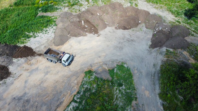 Aerial top-down view of a tipper dump truck at a construction site or quarry with soil heaps