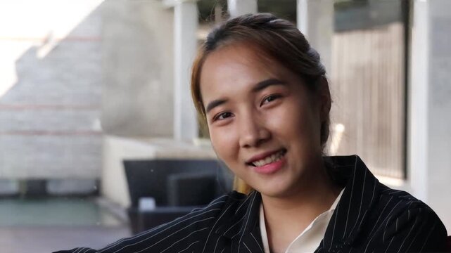 Relaxed and happy Asian business woman or office worker smiling, showing positive face expression