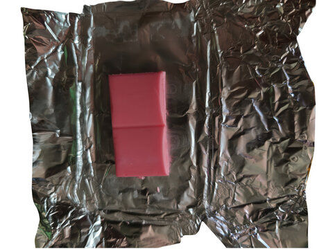 Red square candy piece on shiny silver foil wrapping