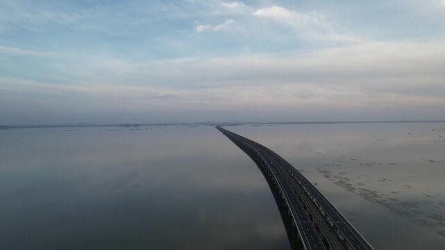 Aerial view of long bridge crossing wide lake at dusk in China