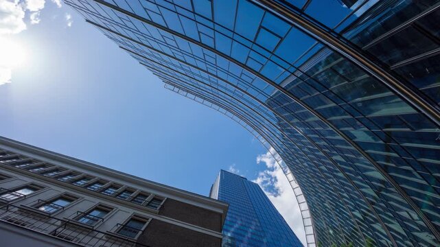 Wide low angle time-lapse of financial district glass skyscrapers and tall office buildings, downtown city center street, modern architecture, blue sky
