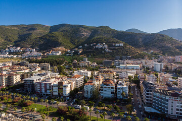 Fototapeta premium Aerial view of Alanya city skyline and Taurus mountains in Turkey. Modern urban architecture, coastal resort real estate, mediterranean landscape and summer travel destination concept. Turkish Riviera