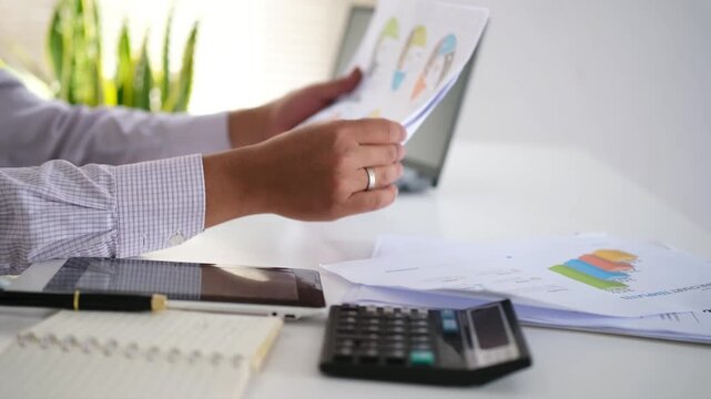 Concept Business working on a report or questionnaire writing notes with a pen and readind financial report analyzing statistics pointing at pie chart working at desk.
