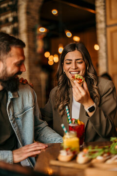 Happy couple enjoying appetizer bruschetta and cocktails on a date