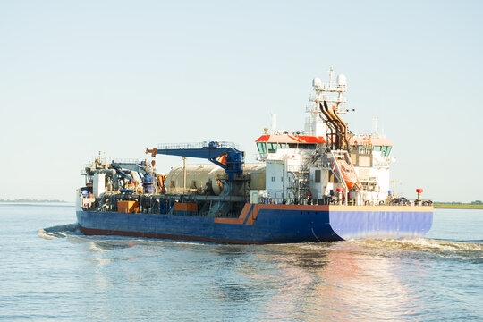 Blue Industrial Hopper Dredger Vessel Navigating Coastal Waterway - The Concept of Marine Construction And Maintenance