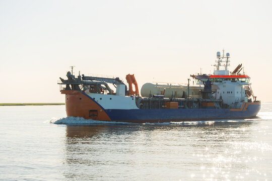 Blue Industrial Hopper Dredger Vessel Navigating Coastal Waterway - The Concept of Marine Construction And Maintenance