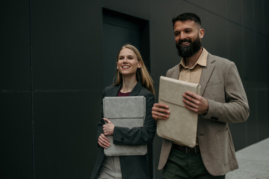 Business people smiling walking successfully with notebooks outdoors