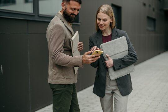 Business colleagues collaborating outdoors using smartphone technology