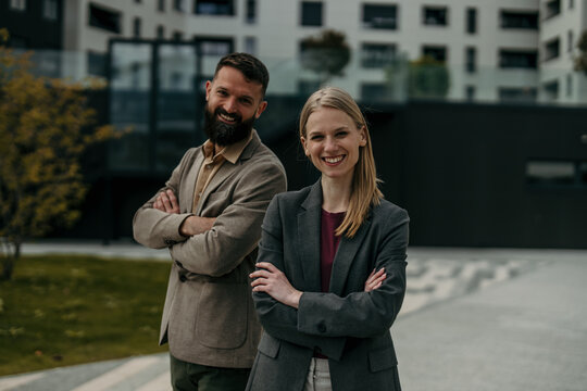 Business partners smiling with arms crossed outdoors