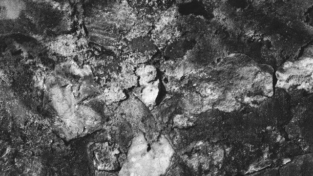 Monochrome old stone and cement wall with patchy mortar, rough rock fragments, and high contrast architectural texture detail.