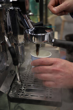 maquina industrial de caf&eacute; sirviendo caf&eacute; en un vaso y barista sujetando el vaso