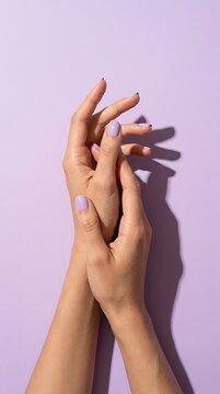Two hands with lavender manicure against a light purple background