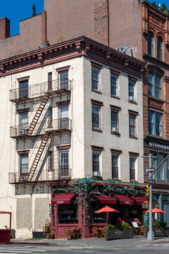 The charming neighborhood life at a classic corner in Chelsea New York containing a residential apartment building and a lively Italian restaurant on the lower floor.
