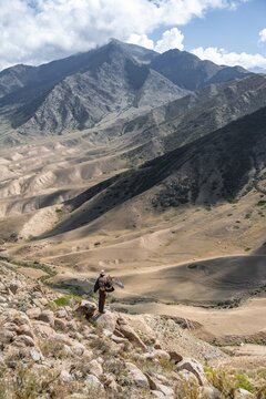 Traditional Kyrgyz eagle hunter hunting in the mountains in a dry landscape, near Kysyl-Suu, Issyk Kul, Kyrgyzstan