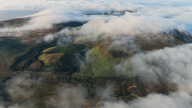 Aerial view of Flores Island with lush green hills and rolling clouds over the landscape in Azores, Portugal.