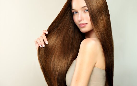 Beautiful model girl with shiny brown and straight long hair . Keratin straightening . Treatment, care and spa procedures. Smooth hairstyle.
