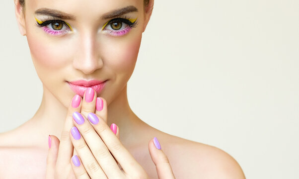 Beautiful model woman with a fashion makeup. Girl spring  pink and lilac manicure nails . Summer image .Make-up,Cosmetology and spa. Care for hands and cosmetics , cream and nail polish