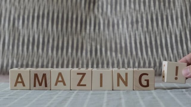 motivational word amazing !, laying out  by hand from letters on wooden cubes, slow motion
