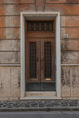 Fototapeta premium Antique wooden door with geometric decorative panels in a stone portal. Ideal for Italian historical architecture real estate and classic design concepts 
