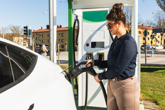 Woman Charging Electric Vehicle at Public Station
