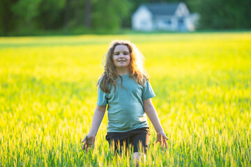 Obraz premium Teenager walking across green meadow. Happy teenager enjoys countryside sunlight. Teenager lifestyle feels active and healthy. Teenager recreation supports youthful freedom.