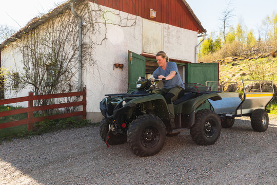 Woman Operating Quad Bike with Trailer on Farm