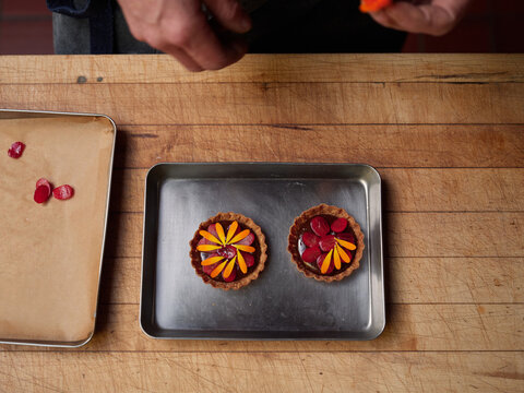 Baker carefully prepares dessert on wooden table in kitchen