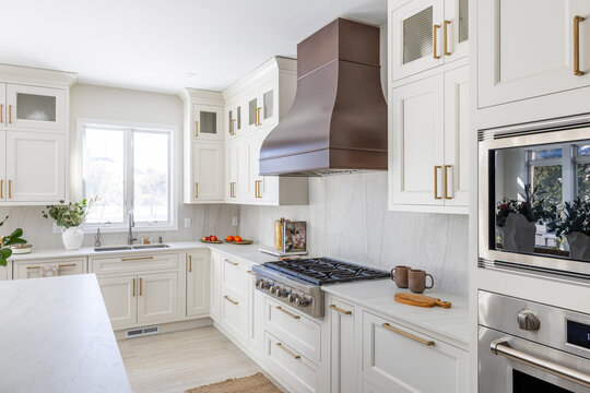 Modern White Kitchen with Marble Countertops, Gold Hardware and Stainless Steel Range

