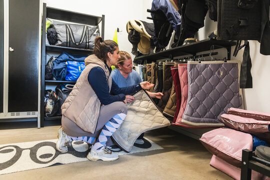 Equestrians Choosing Quilted Saddle Pads in Tack Room