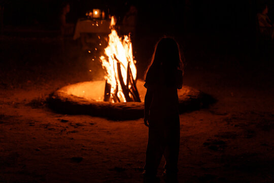 Child Stands Near a Campfire at Night. Sri Lanka