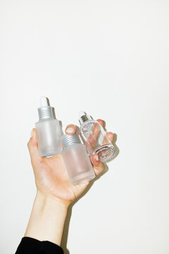 Hand holding simple minimal glass beauty cosmetic pipette bottles 
