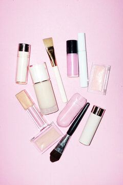 Cute pink makeup products: blush, lip gloss, highlighter, foundation