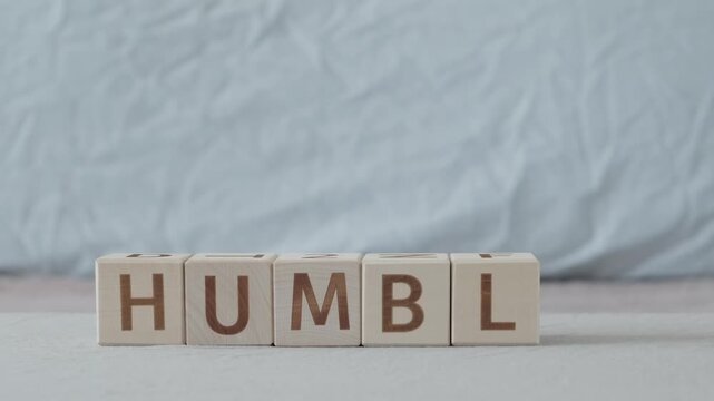 motivational word humble, laying out  by hand from letters on wooden cubes, slow motion
