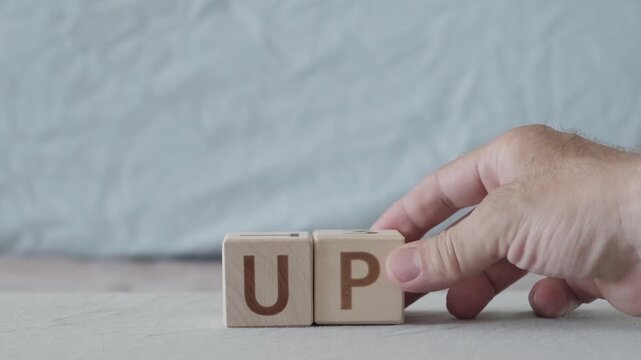 motivational word up, laying out  by hand from letters on wooden cubes, slow motion
