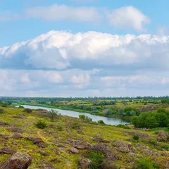 view from  green rocky hills to the river in the canyon under a blue cloudy sky © Yuriy Kulik